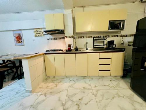 a kitchen with white cabinets and a marble floor at Welcome Home in Bogotá