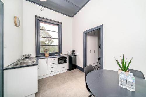 a kitchen with a table and a sink at The Hampden Suites in Wagga Wagga