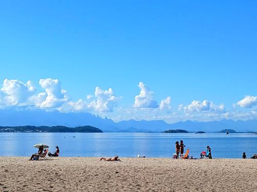 a group of people on a beach near the water at Quarto Privado Cama Casal e Individuais Apto in Rio de Janeiro