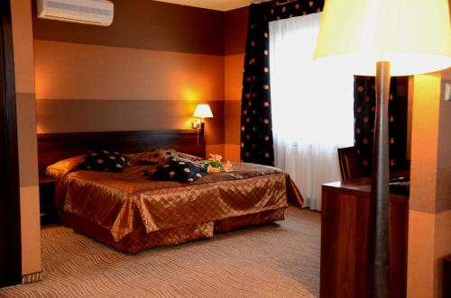 a bedroom with a bed with a lamp and a window at Hotel Azalia & Spa in Niepołomice