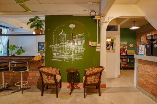 a green wall with a drawing of a house on it at Auntie & Niece PHUKET in Ban Sam Kong