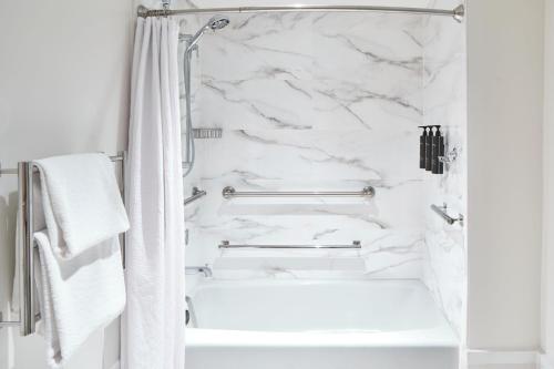 a white bathroom with a marble shower curtain and a bathtub at La Concha Key West, Autograph Collection in Key West