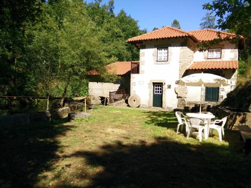 a house with a table and chairs in the yard at Moinho da Cruz in Ponte de Lima