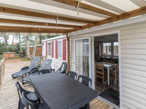 un patio avec une table et des chaises sur une terrasse dans l'établissement Mobil-home 6 pers, camping 3 étoiles à 5km de l'océan, piscine chauffée, activités familiales - FR-1-50-144, à Saint-Julien-en-Born