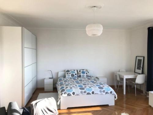 a white bedroom with a bed and a table at 6 minutes à pied de la Gare de Lausanne in Lausanne