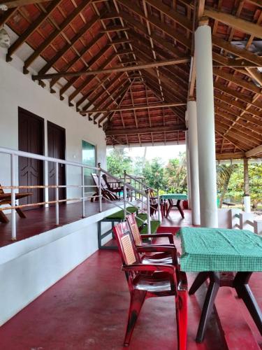 a porch with chairs and a table and a balcony at Marari Praise Beachfront Homestay in Mararikulam