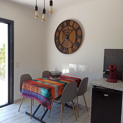 une salle à manger avec une table et une horloge au mur dans l'établissement Meublé Tourisme 3 Etoiles Labell 'Accueil Vélo', à Hérépian