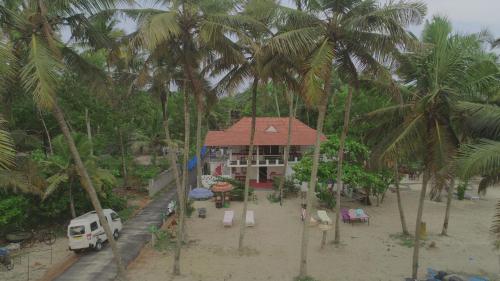 a house on the beach with palm trees at Marari Praise Beachfront Homestay in Mararikulam