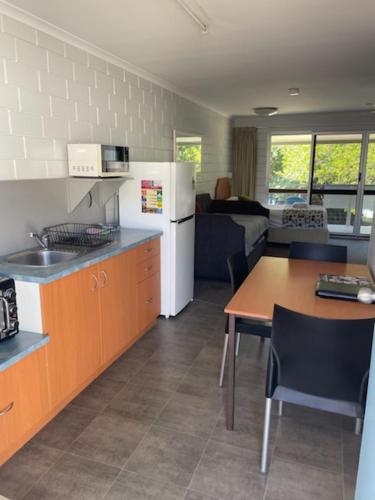 Una cocina y un comedor con una mesa y un refrigerador. en Whitehaven Beachfront Holiday Units, en Airlie Beach