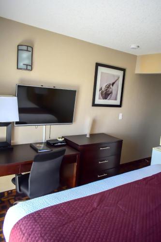a hotel room with a bed and a desk with a television at Days Inn by Wyndham Sylvan Lake in Sylvan Lake