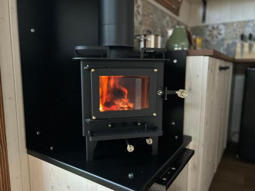 a stove in a kitchen with a fire in it at Maringotka u Krkavčích skal in Křižany