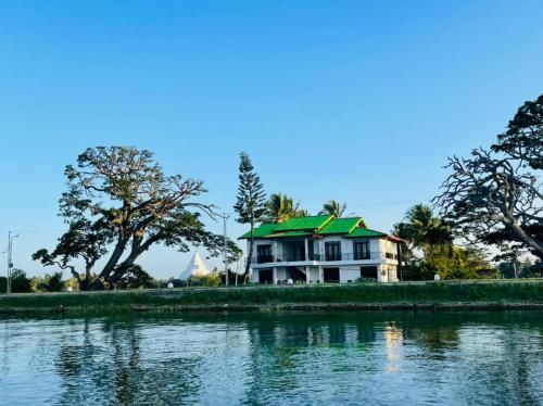 a house with a green roof next to a body of water at Tissa Yala Lake View Hotel in Tissamaharama