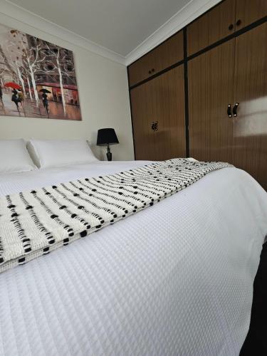 a white bed in a bedroom with a picture on the wall at Fitzroy Lodge Cowra in Cowra