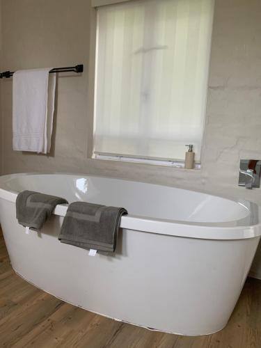 a white bath tub in a bathroom with towels at Above Par Kingswood in George