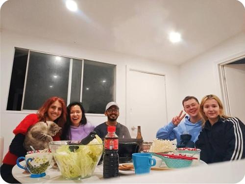 a group of people sitting at a table in a kitchen at Stylish Queen Room 1Min Walk to Station 5Min to City 10Min to Airport in Sydney