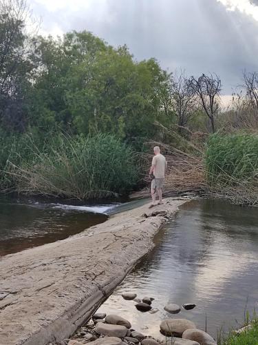 a man standing on the shore of a river at De Oude Yotclub in Oudtshoorn