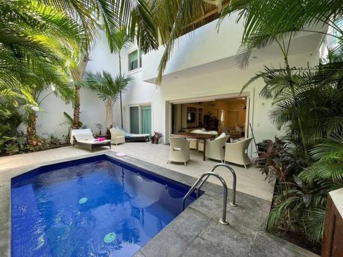 a swimming pool in front of a house with palm trees at Casa de lujo con alberca y playa privada in Cruz de Huanacaxtle