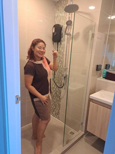 a woman standing in a bathroom with a shower at Cybiq Ratchada 32 by Pikul in Bangkok