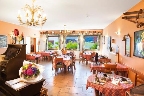 a restaurant with tables and chairs and a piano at Hôtel-Restaurant Le Lac in Malbuisson