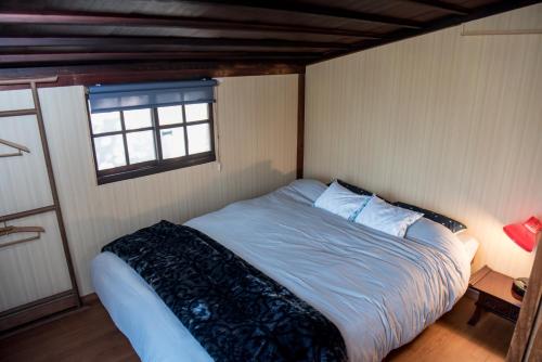 a bed in a small room with a window at Benton Guesthouse, Private Nostalgic Showa-era House, former "Akiya" in Imabari