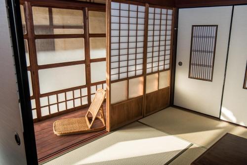 a room with a door and a wicker chair at Benton Guesthouse, Private Nostalgic Showa-era House, former "Akiya" in Imabari