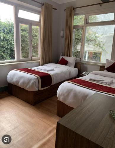 two beds in a room with two windows at Buddha Home Nepal in Thapathali
