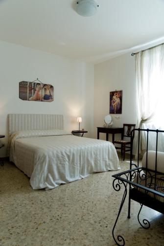 a white bedroom with a large bed and a chair at La Rocca in Pergola