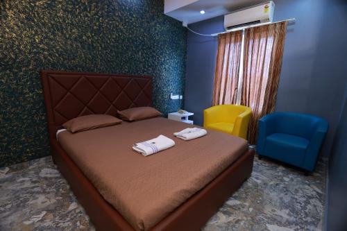 a bedroom with a bed and a blue chair at Hotel Reech in Nāgercoil