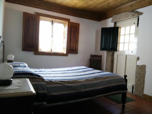 a bedroom with a bed and two windows at Moinho da Cruz in Ponte de Lima