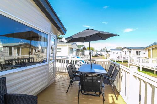 a patio with a table and chairs and an umbrella at Brilliant 8 Berth Caravan Near Walton-On-The-Naze In Essex - 17023Nm in Walton-on-the-Naze