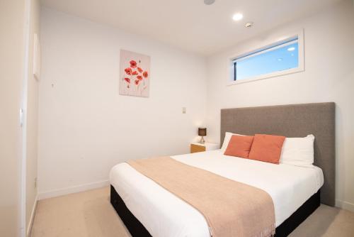 a bedroom with a large white bed with a window at Gorgeous High Floor Skytower view 2 Bedroom Apartment in Auckland CBD in Auckland