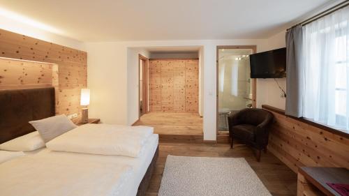 a bedroom with a bed and a chair and a television at Ansitz Velseck-Residence Hotel in Tires