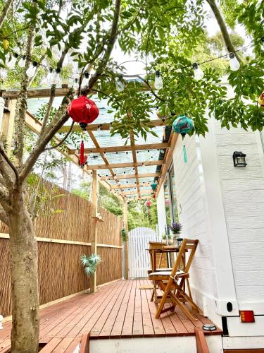 a patio with a tree and a wooden pergola at Tiny Amor in Berkeley Vale