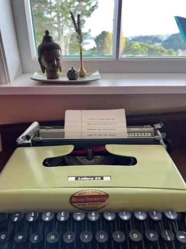 an old typewriter with a head on it next to a window at Fridas Accommodation in Raglan