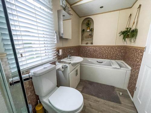 a bathroom with a toilet and a sink and a tub at Beautiful Caravan At Manor Park In Hunstanton Beach, Norfolk Ref 23026H in Hunstanton