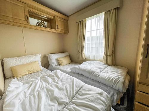 a room with two beds and a window at Beautiful Caravan At Manor Park In Hunstanton Beach, Norfolk Ref 23026H in Hunstanton