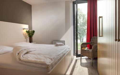 a bedroom with a bed and a chair and a window at Hotel Termal Mušov in Pasohlávky