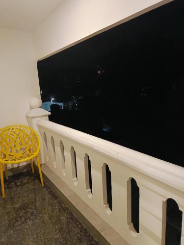 a yellow chair in a room with a large window at ELZAS FORT iNN in Cochin