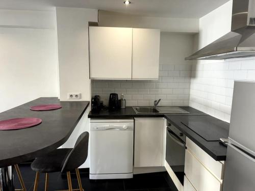 une cuisine avec des armoires blanches et un comptoir noir dans l'établissement Grand Studio Centre Cannes, à Cannes