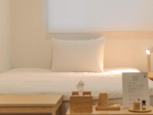 a bedroom with a bed with white sheets and pillows at RAK KIYOMIZU - for one person - 1人旅専用HOSTEL in Kyoto