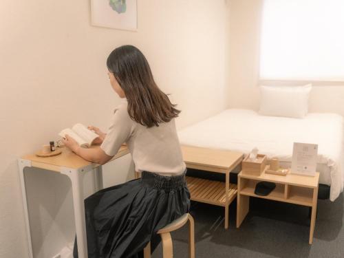 a woman is standing at a desk in a room at RAK KIYOMIZU - for one person - 1人旅専用HOSTEL in Kyoto