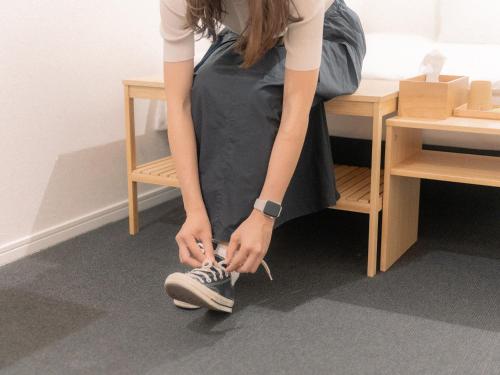 a woman tying her shoes in a room at RAK KIYOMIZU - for one person - 1人旅専用HOSTEL in Kyoto