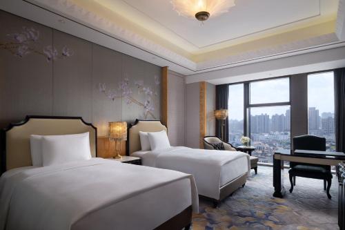 a hotel room with two beds and a desk at The St. Regis on the Bund, Shanghai in Shanghai