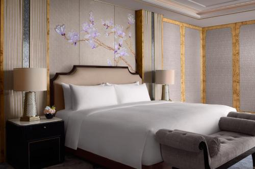 a bedroom with a large white bed and a chair at The St. Regis on the Bund, Shanghai in Shanghai