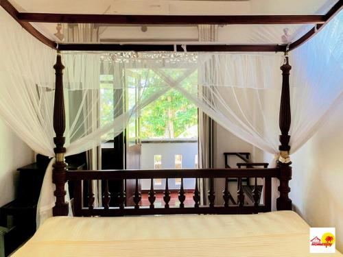 a bedroom with a canopy bed with a window at Uyanawatta villa talpe in Talpe