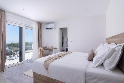 a white bedroom with a large bed and a balcony at Villa Skyora in Trogir