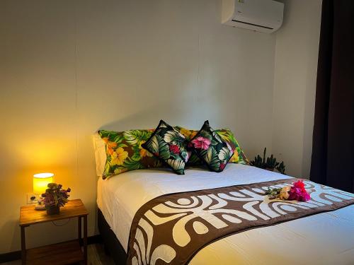 a bedroom with a bed with colorful pillows at Heinani Lodge Tiahura in Moorea
