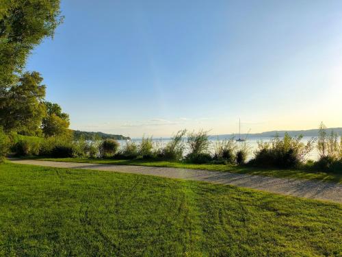 a path through a park with the water in the background at Helle Wohnung in Seenähe in Berg am Starnberger See