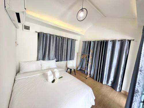 a white bed in a room with gray curtains at Sapa pool villa in Loei