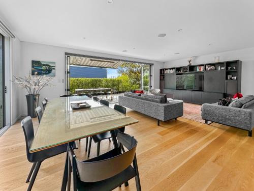 a living room with a table and a dining room at Orakei Oasis l Quality 3 Bed House inc Views in Auckland